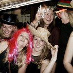 Five women are laughing and posing together, wearing fun hats and wigs—including a pink wig and a sparkly black hat—celebrating New Years Eve 2019 in front of a large ornate picture frame. Five women are laughing and posing together, wearing fun hats and wigs—including a pink wig and a sparkly black hat—celebrating New Years Eve 2019 in front of a large ornate picture frame.