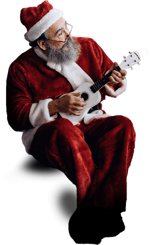 A man dressed in a Santa Claus outfit, with a white beard and glasses, sits while playing a small white ukulele.